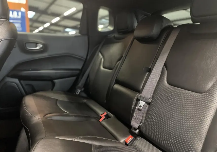 Vue latérale droite de la banquette arrière en cuir noir du Jeep Compass avec ceinture de sécurité grise visible.