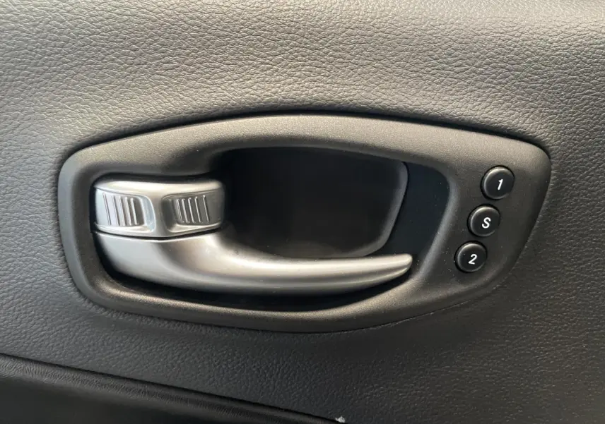 Poignée intérieure de porte noire avec boutons de réglage mémoire des sièges dans une Jeep Compass Trailhawk.