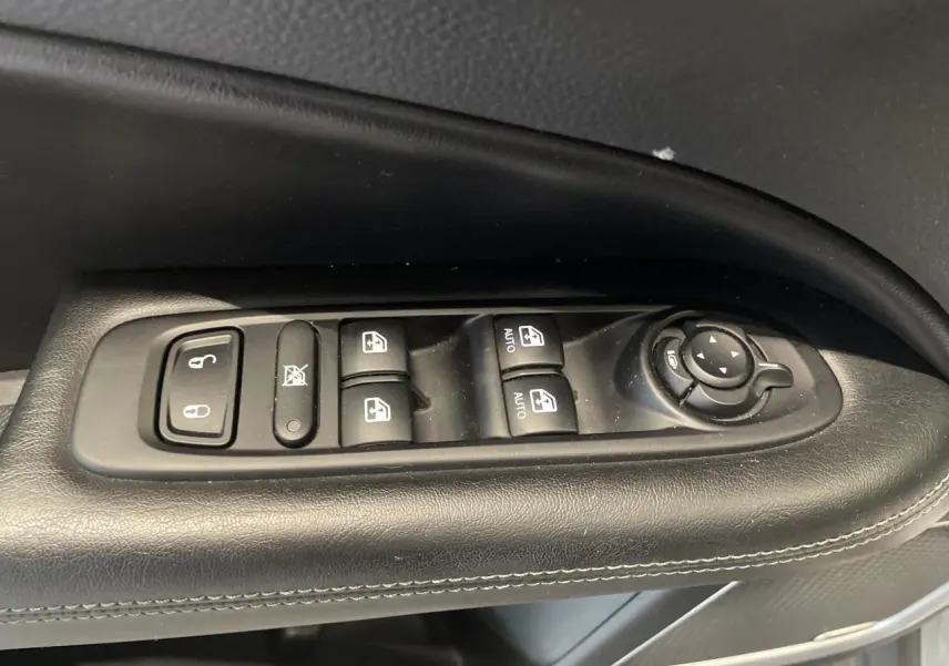 Gros plan sur les commandes électriques des vitres et rétroviseurs sur la porte côté gauche du Jeep Compass gris foncé.