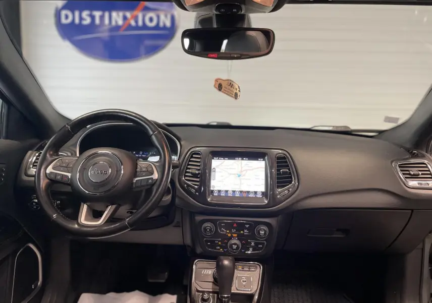Intérieur noir du Jeep Compass 2021 vu de face, tableau de bord avec écran tactile GPS et volant cuir multifonction.