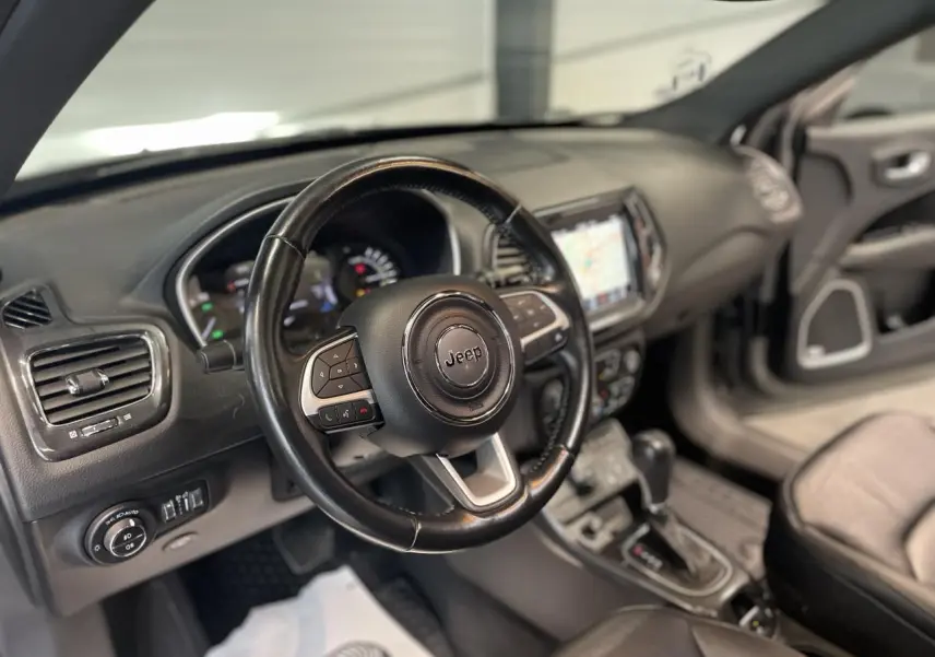 Vue intérieure du volant cuir noir et tableau de bord du Jeep Compass 2021 avec écran tactile et commandes au volant.