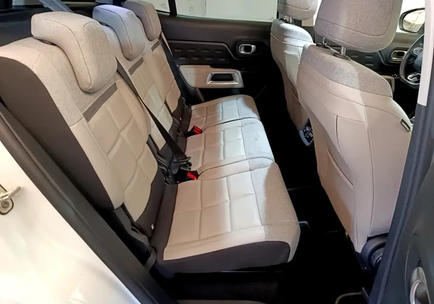 Vue latérale intérieure sur les sièges arrière beige et gris du Citroën C5 Aircross Hybrid blanc, avec ceinture de sécurité visible.
