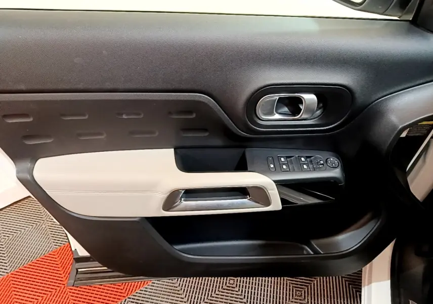 Vue intérieure sur la porte avant gauche du Citroën C5 Aircross blanc, avec garniture noire et beige et commandes électriques.