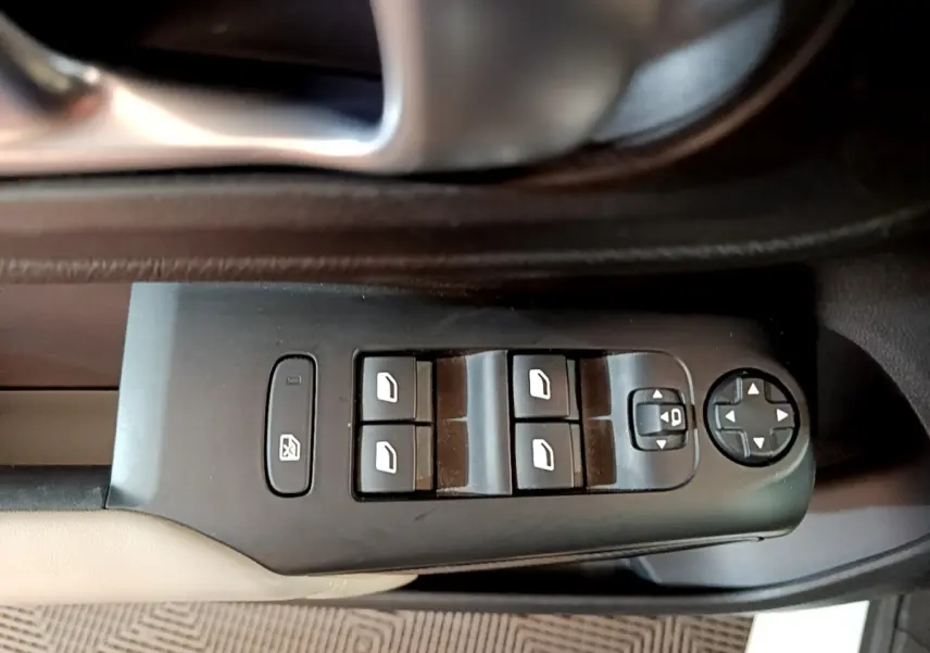 Vue rapprochée des commandes de lève-vitres et rétroviseurs sur la porte intérieure noire et beige d'une Citroën C5 Aircross blanche.