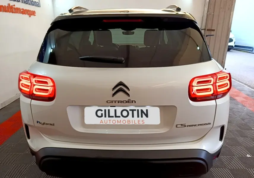 Vue arrière du Citroën C5 Aircross Hybrid blanc, feux arrière LED allumés et logo distinctif au centre du hayon.