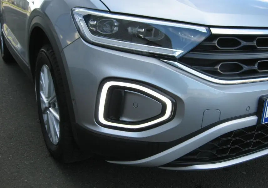 Gros plan sur l’avant droit gris clair du Volkswagen T-Roc 2023, mettant en valeur le phare LED et la signature lumineuse distinctive.