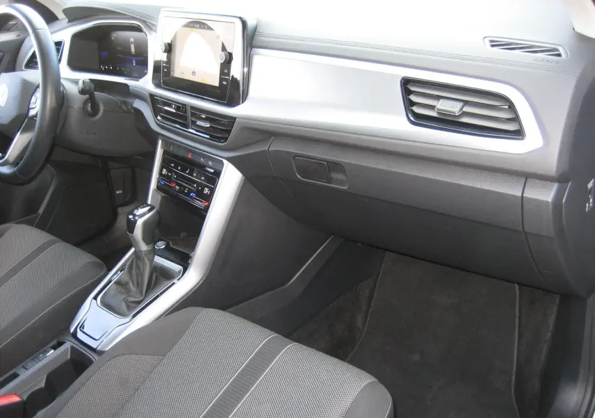 Vue intérieure côté passager du tableau de bord et console centrale du Volkswagen T-Roc 1.5 TSI gris clair avec boîte automatique.