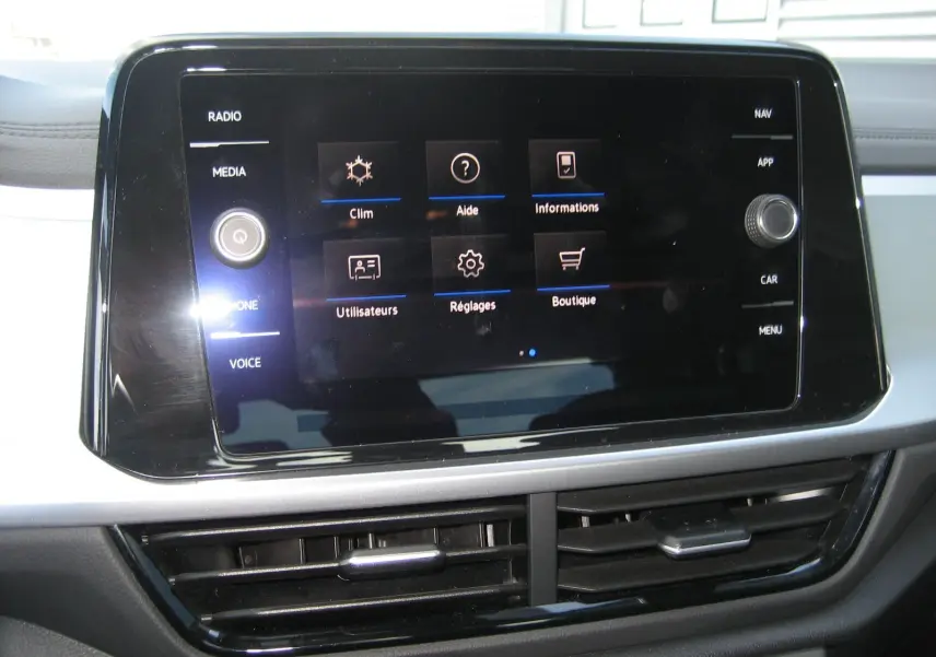 Écran tactile central du Volkswagen T-Roc 2023 affichant le menu principal avec commandes climatisation et réglages.