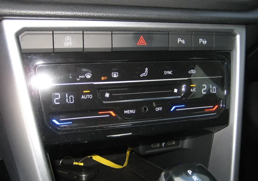Gros plan sur la console centrale du Volkswagen T-Roc gris clair 2023, affichant la climatisation digitale et la boîte automatique.