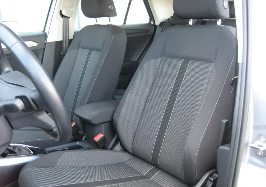 Vue intérieure sur les sièges avant gris foncé du Volkswagen T-Roc 2023, avec accoudoir central et volant partiel visible.