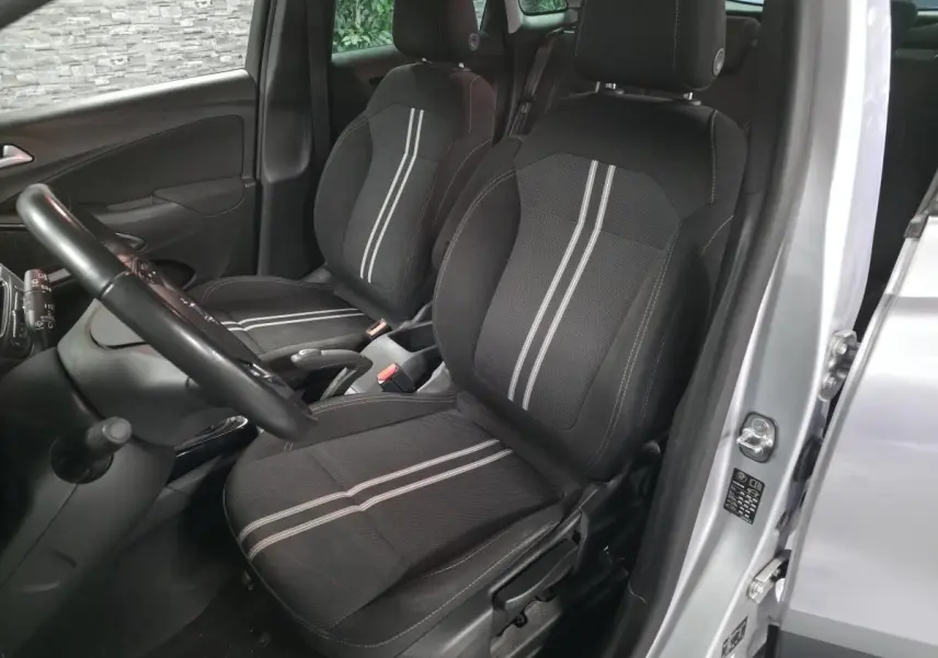 Vue intérieure côté conducteur de l’Opel Crossland gris 2023, avec sièges tissu noir à bandes grises et volant visible.