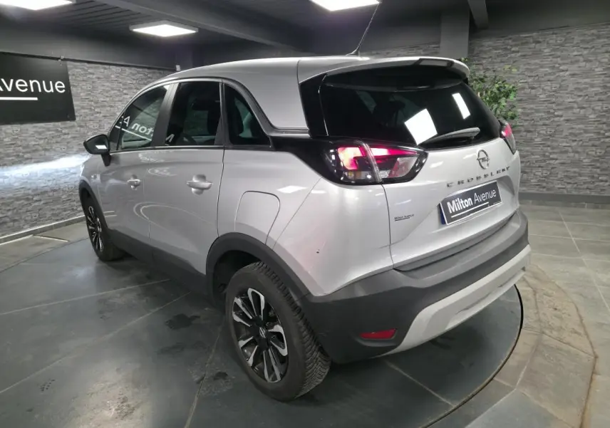 Opel Crossland gris métallisé vu en 3/4 arrière droit, avec jantes alliage noires et toit noir contrasté.