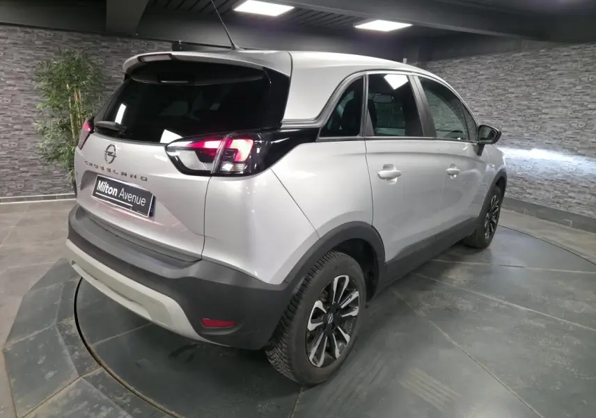 Vue 3/4 arrière droite d'un Opel Crossland gris métallisé avec jantes alliage noires et toit noir contrasté.