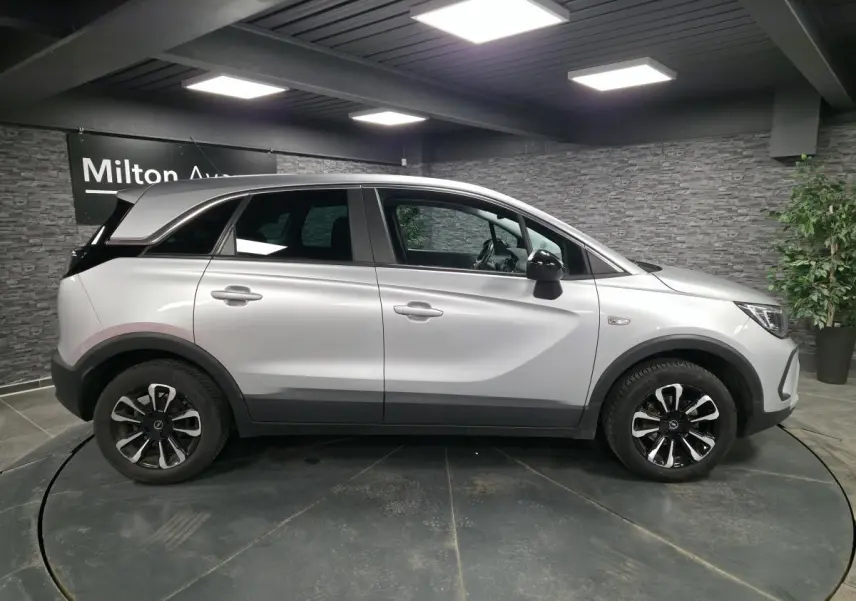 Opel Crossland gris métallisé vue de profil côté gauche avec jantes alliage noires et coques de rétroviseurs noir Karbon.