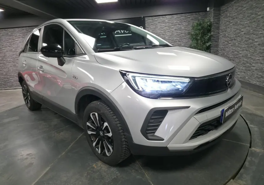 Opel Crossland gris métallisé en 3/4 avant droit, avec phares LED allumés et jantes alliage bicolores.
