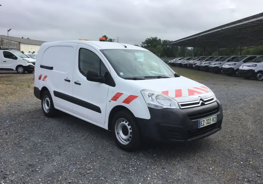 Vue 3/4 avant droite d'un Citroën Berlingo blanc avec bandes rouges réfléchissantes et gyrophare orange sur le toit.