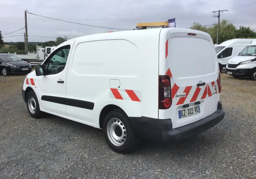 Vue 3/4 arrière droite d’un utilitaire Citroën Berlingo blanc avec bandes réfléchissantes rouges et gyrophare sur le toit.