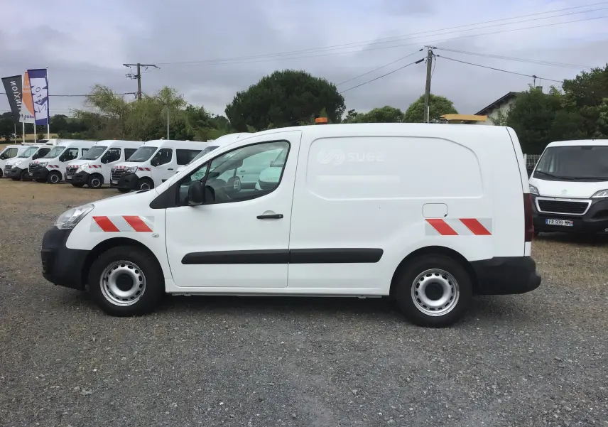Vue de profil côté gauche d’un Citroën Berlingo XL blanc utilitaire avec bandes rouges diagonales et gyrophare orange sur le toit.