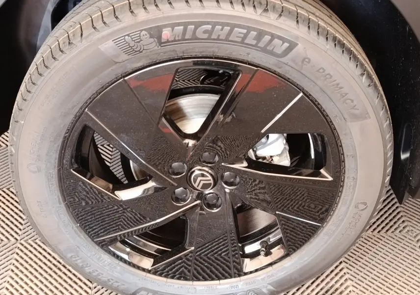 Gros plan sur la roue avant droite avec jante noire brillante et pneu Michelin sur Citroën C5 hybride vert.