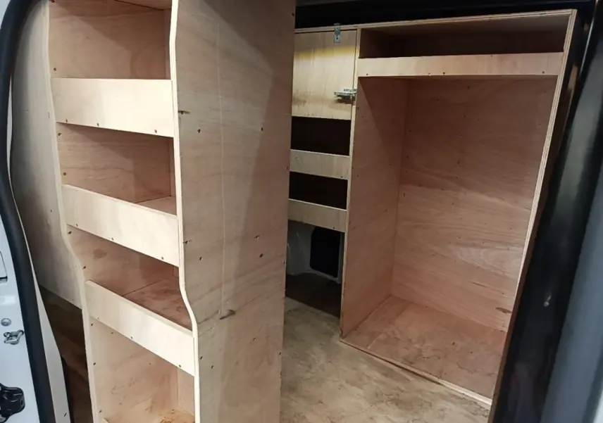 Vue intérieure du fourgon Peugeot Expert blanc, montrant l'aménagement bois avec étagères et compartiments de rangement.