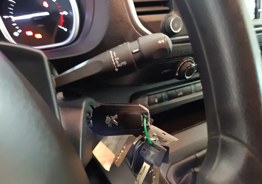 Gros plan sur le contact avec clé Peugeot insérée, volant noir et commandes du tableau de bord du Peugeot Expert Fourgon blanc.