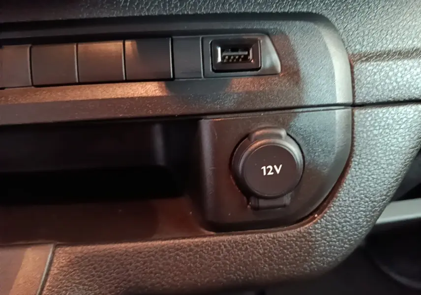 Gros plan sur la prise 12V et port USB du tableau de bord noir du Peugeot Expert Fourgon blanc 2023.