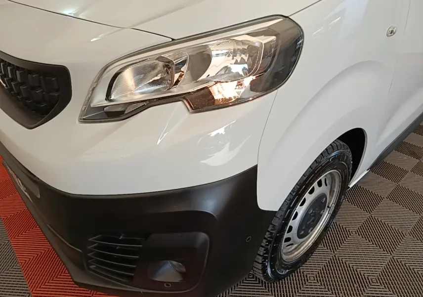 Gros plan sur l'avant droit blanc du Peugeot Expert Fourgon 2023, avec phare allumé et pare-chocs noir mat.