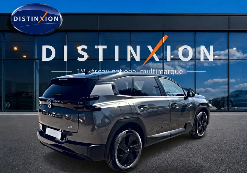 Vue 3/4 arrière droite du Citroën C5 Aircross gris platinium avec toit noir et jantes alliage noires devant un showroom.
