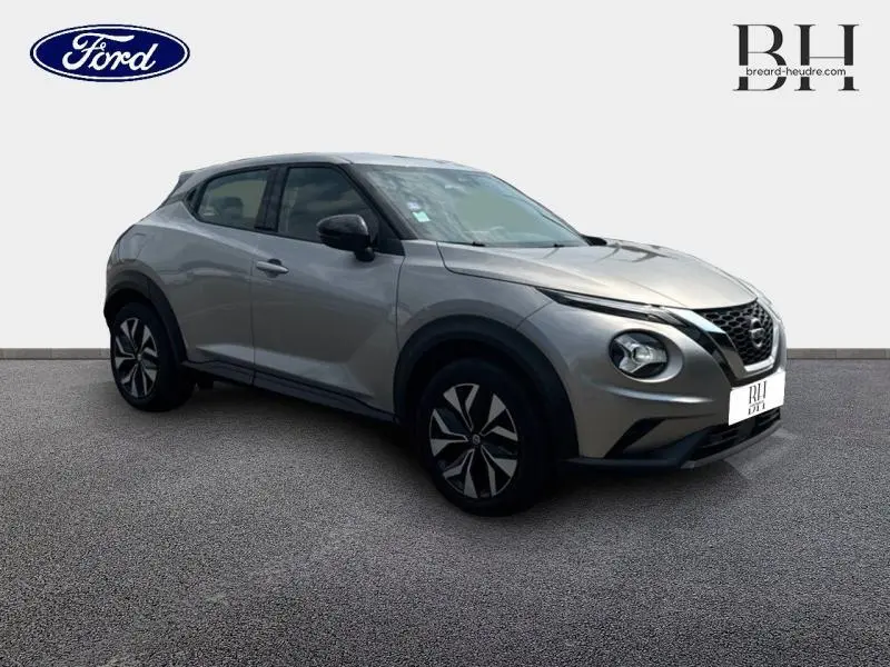 Nissan Juke 2023 gris perle métallisé en 3/4 avant droit, avec phares LED et jantes noires distinctives.