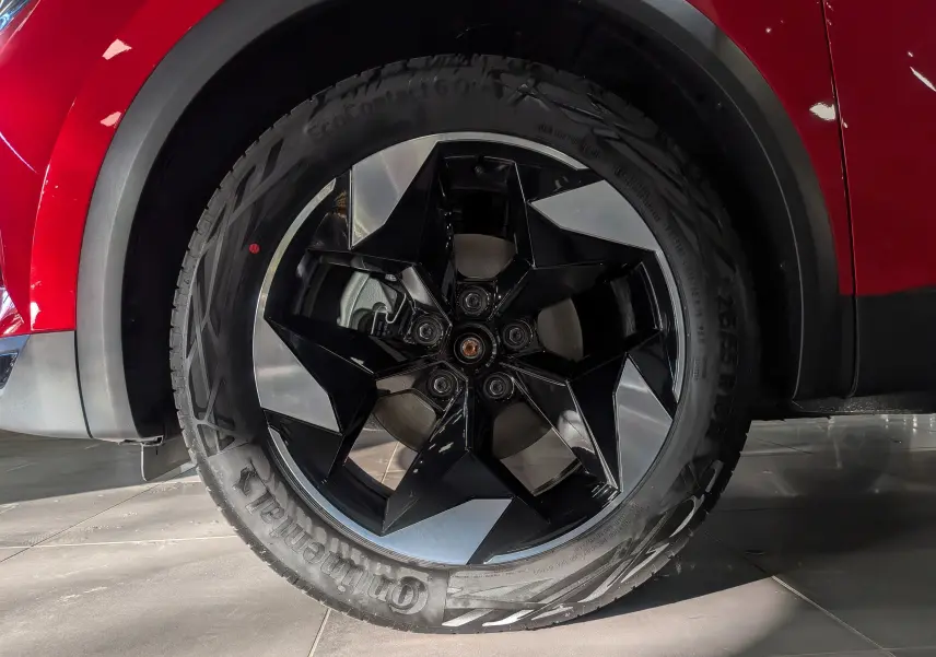 Gros plan sur la roue avant droite du Renault Captur E-TECH rouge Flamme avec jante noire et argentée au design géométrique.