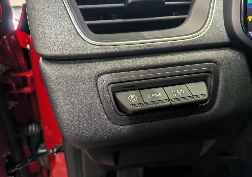 Gros plan sur les commandes E-SAVE et réglage des phares du tableau de bord du Renault Captur rouge Flamme 2025.