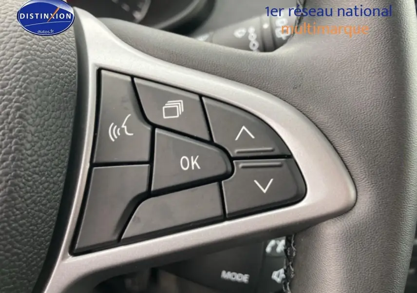 Gros plan sur les commandes multifonctions noires à gauche du volant du Dacia Jogger 2025, intérieur gris.