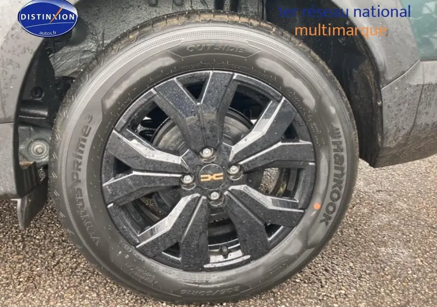 Gros plan sur la roue avant gauche du Dacia Jogger 2025 vert cèdre avec jante alu noire à design moderne.