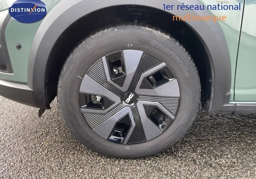 Gros plan sur la roue avant gauche d’un Dacia Jogger gris schiste métal avec jante au design géométrique noir et gris.