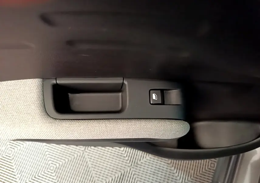 Gros plan sur la poignée intérieure et le bouton de lève-vitre côté porte avant droit du Citroën C3 Aircross gris foncé.