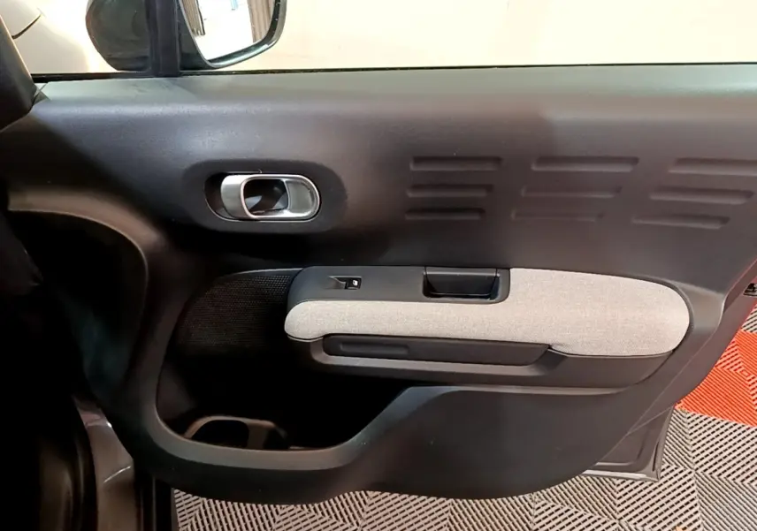 Vue intérieure côté gauche de la porte avant d'une Citroën C3 Aircross 2020 gris foncé avec accoudoir tissu clair.