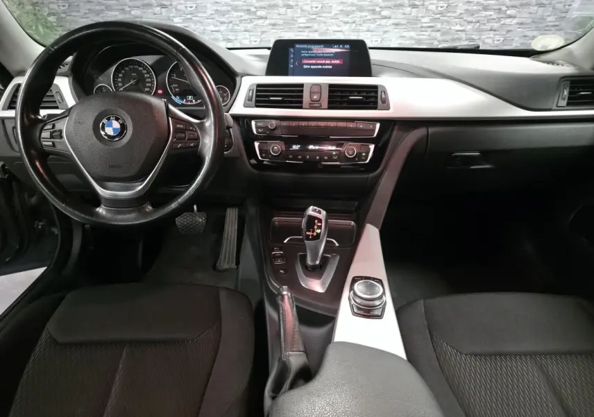 Vue intérieure frontale du poste de conduite de la BMW Série 4 420d Gran Coupé avec volant cuir et console centrale argentée.