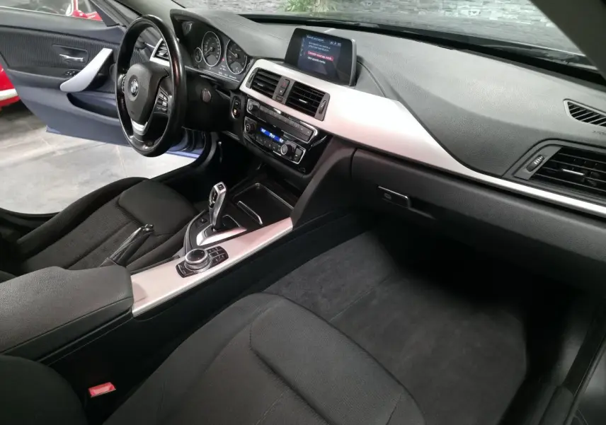 Vue intérieure côté conducteur de la BMW Série 4 Gran Coupé 420d, avec console centrale aluminium satiné et écran multimédia.