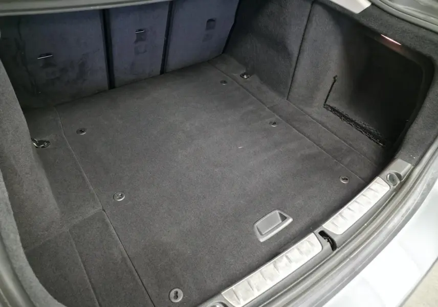 Vue intérieure du coffre spacieux et propre de la BMW Série 4 Gran Coupé gris foncé, avec tapis en tissu anthracite.