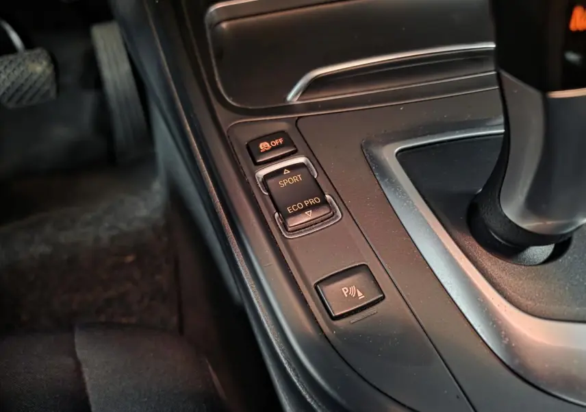 Gros plan sur la console centrale de la BMW Série 4 420d xDrive, boutons de mode conduite et radar de stationnement.