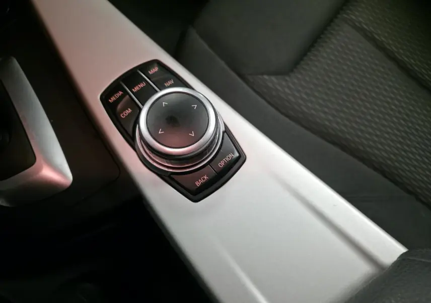 Gros plan sur la molette de commande iDrive et la console centrale aluminium satiné de la BMW Série 4 gris foncé.