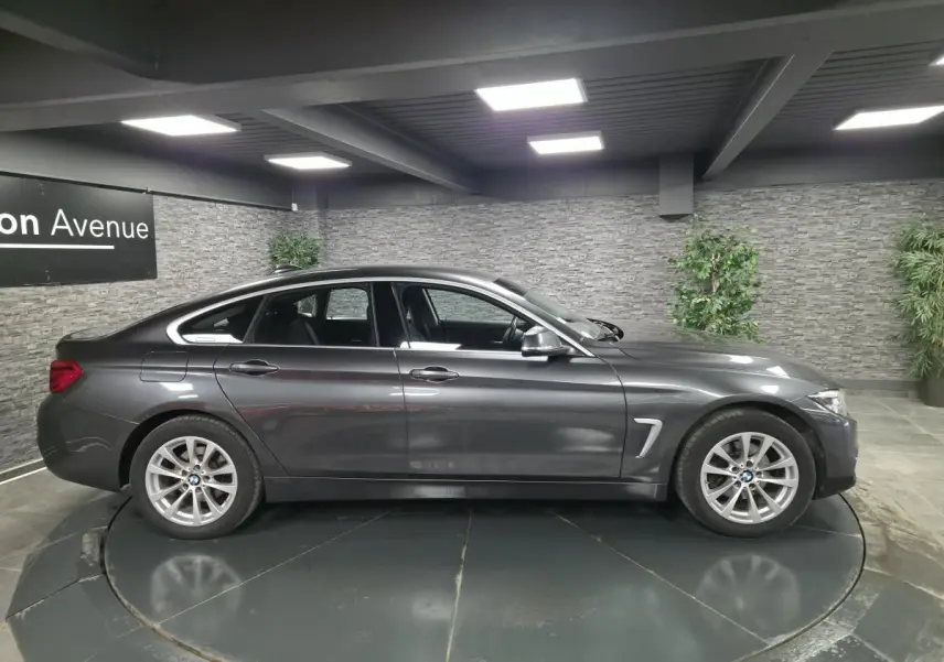 BMW Série 4 Gran Coupé gris foncé vue de profil côté gauche, avec jantes alliage et détails chromés.