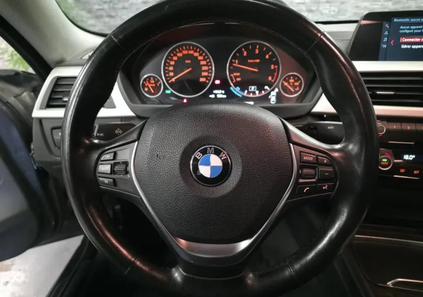 Vue intérieure centrée sur le volant cuir noir de la BMW Série 4 420d Gran Coupé avec tableau de bord et écran multimédia.