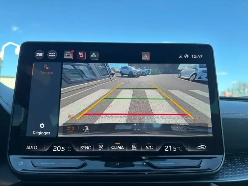 Vue arrière en caméra de recul d'un CUPRA Formentor blanc Nevada métallisé avec lignes de guidage sur un passage piéton.