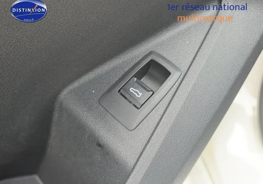 Détail du bouton d'ouverture de coffre sur la porte intérieure d'une BMW Série 1 blanche pure.