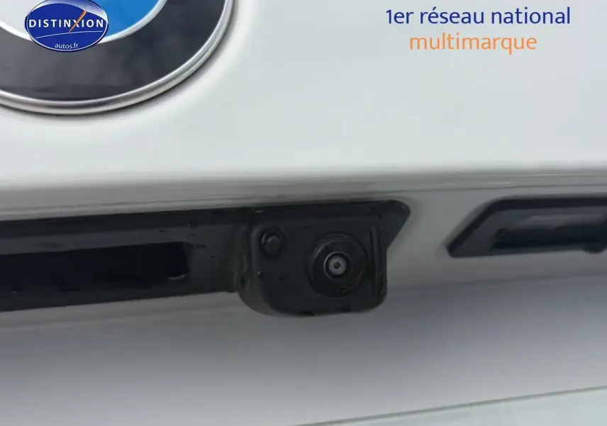 Gros plan sur la caméra de recul noire intégrée à l'arrière d'une BMW Série 1 blanche pure.