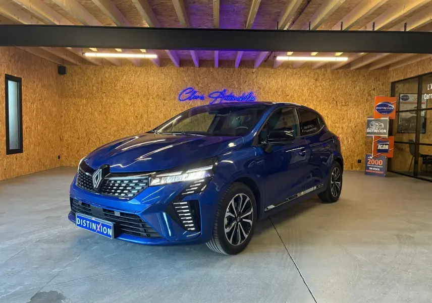 Renault Clio V E-TECH 145 TECHNO bleu iron vue 3/4 avant en intérieur avec éclairage LED et jantes bi-ton.