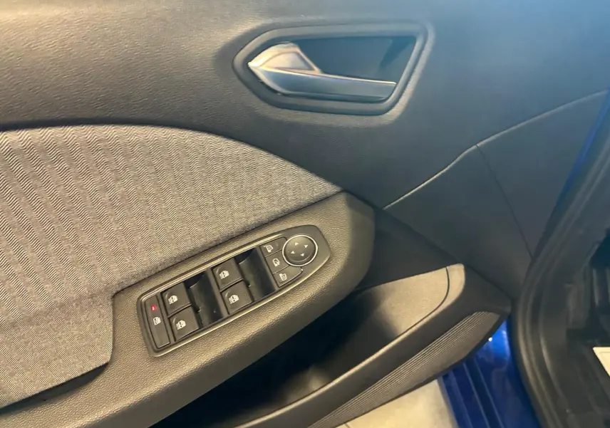 Détail de la porte côté conducteur de la Renault Clio V E-Tech 145 Techno bleu Iron, avec commandes des vitres et poignée intérieure.