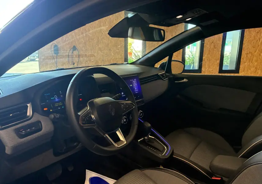 Vue intérieure côté conducteur de la Renault Clio V E-TECH 145 TECHNO 2025 avec tableau de bord numérique et console centrale éclairée.