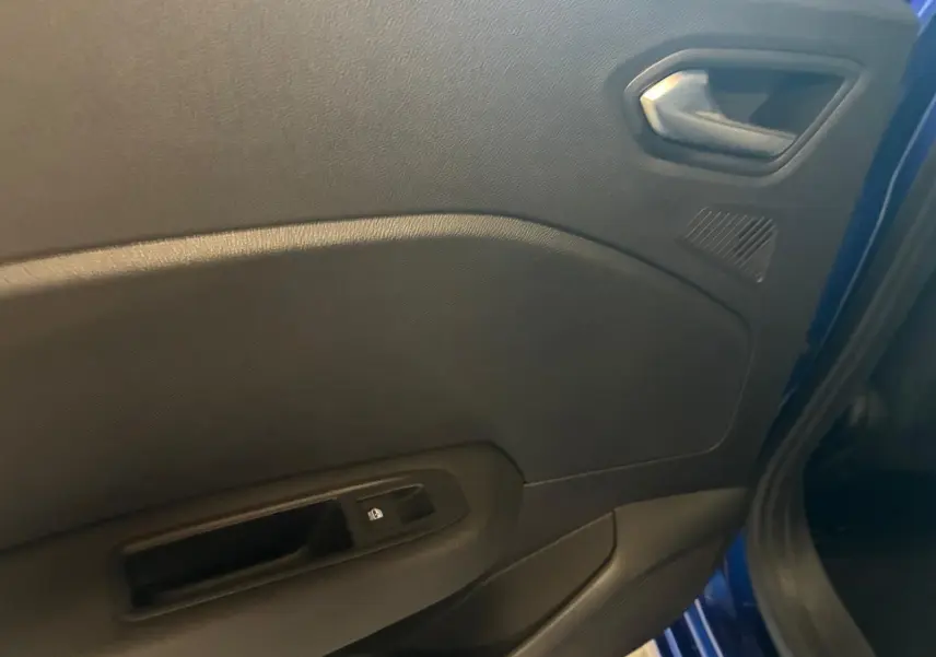 Vue intérieure de la porte avant droite d'une Renault Clio Bleu Iron, avec poignée et commande de vitre électrique.